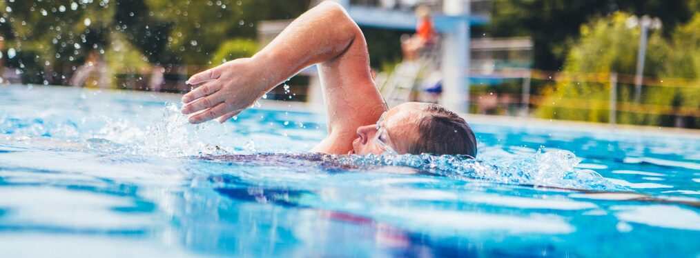 Eine Frau schwimmt im Freibad.
