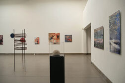 Das Foto zeigt einen Ausstellungsraum mit Bildern an den Wänden und Skulpturen und im Raum.